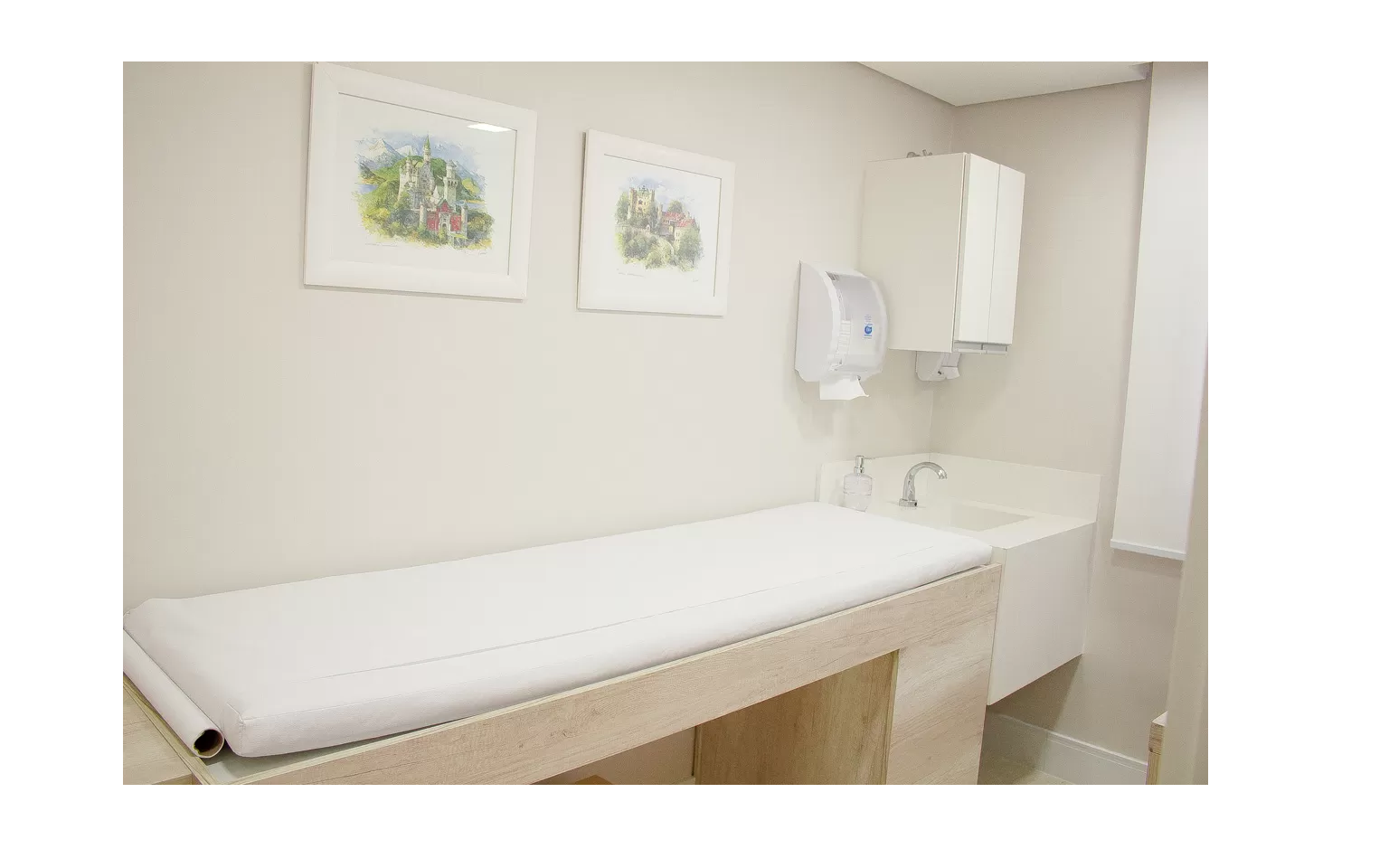 Sala de exame do consultório, com maca preparada para avaliação dermatológica