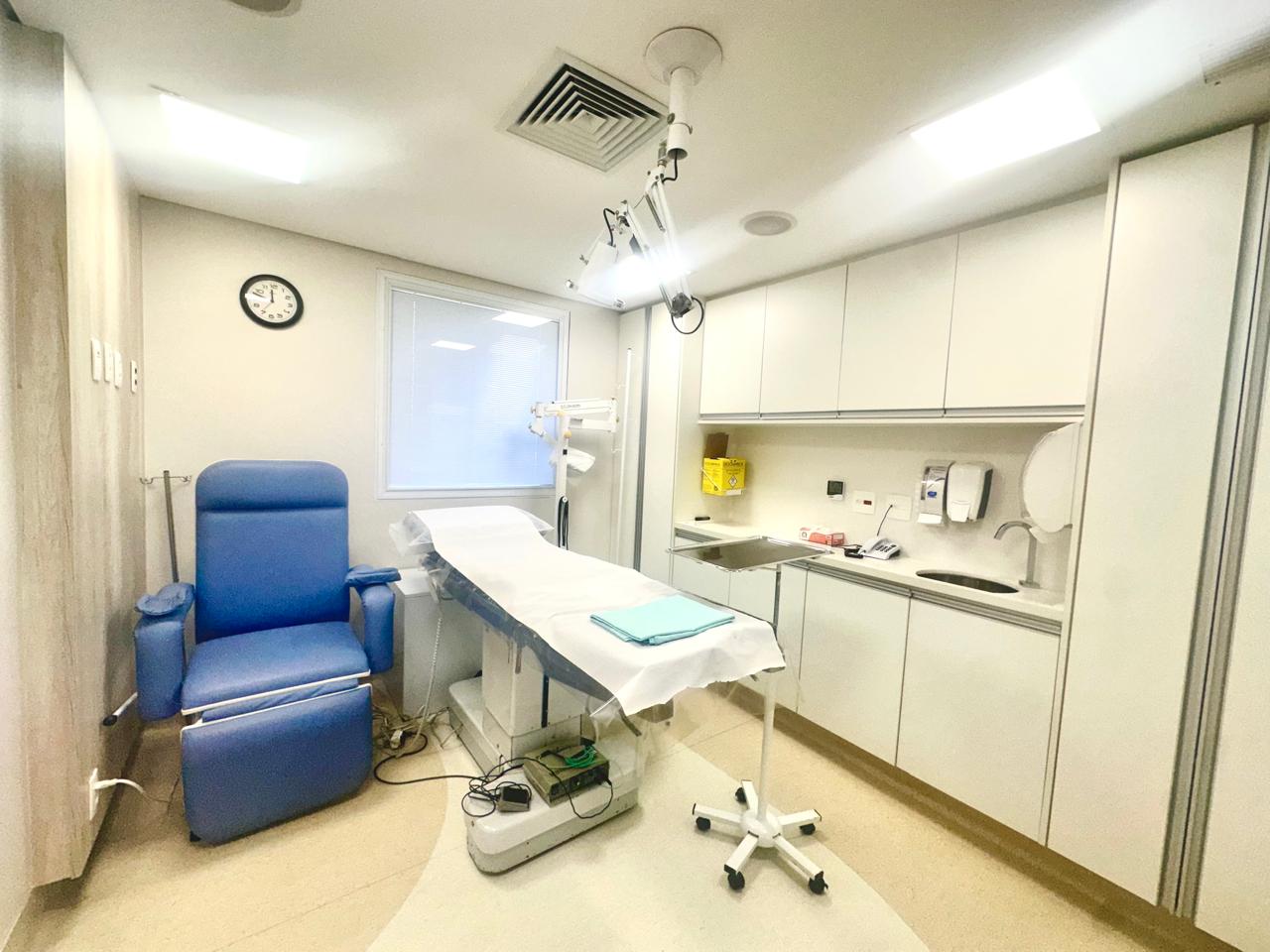 Sala de procedimentos com poltrona reclinável, maca cirúrgica e foco de luz