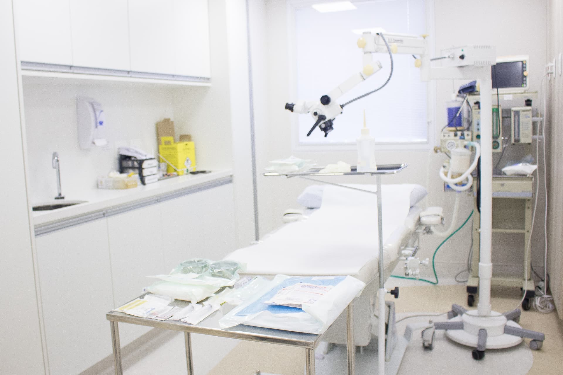 Sala cirúrgica preparada para cirurgia dermatológica, com maca, mesa de instrumentais e equipamentos