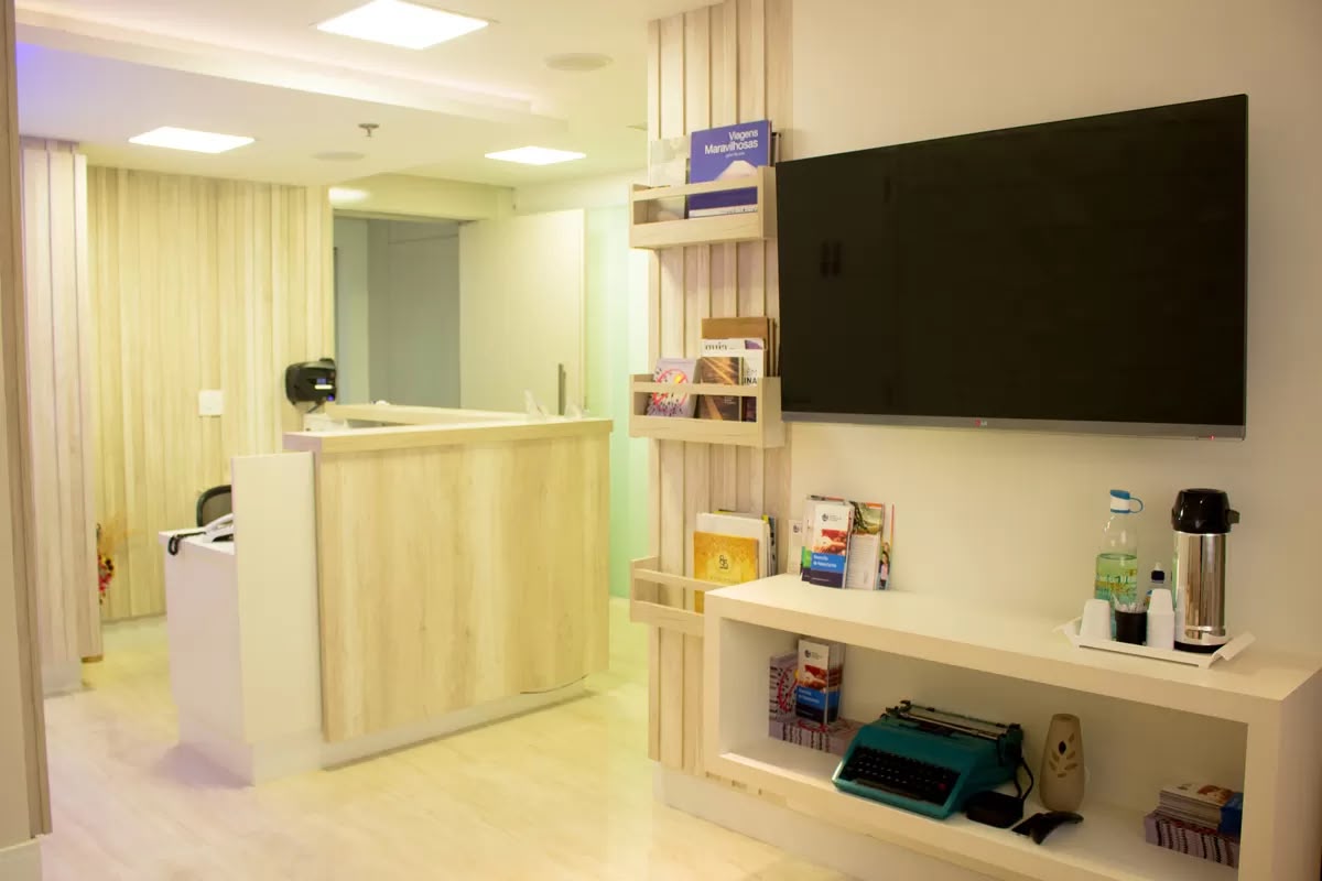 Recepção da clínica, com balcão de atendimento e sala de espera